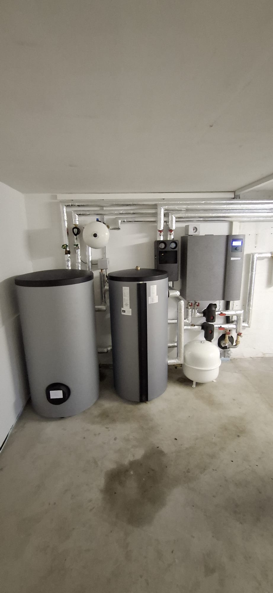 Wärmepumpen-Innenaufbau mit Pufferspeicher, Warmwasserspeicher und Regeltechnik in einem modern ausgestatteten Technikraum.